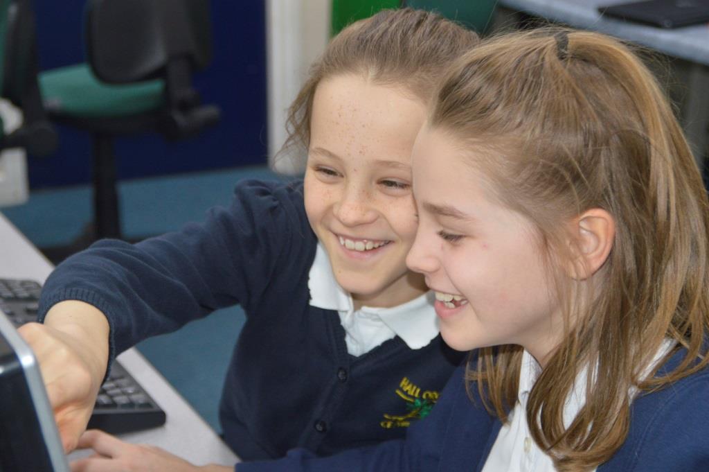 Two girls smiling, using technologhy